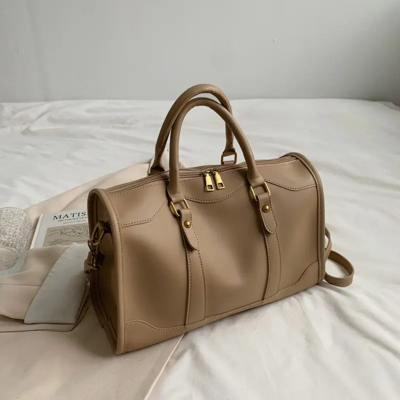 Beige handbag on a white surface with a newspaper underneath