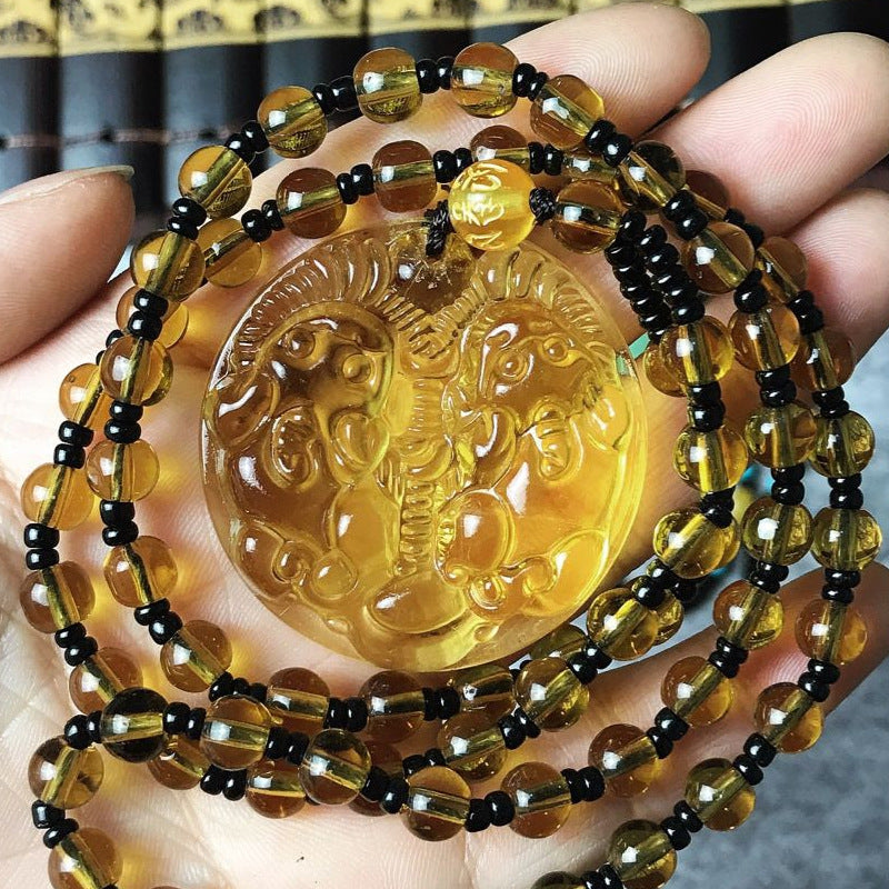 Amber-colored beaded necklace with a central pendant held in hand