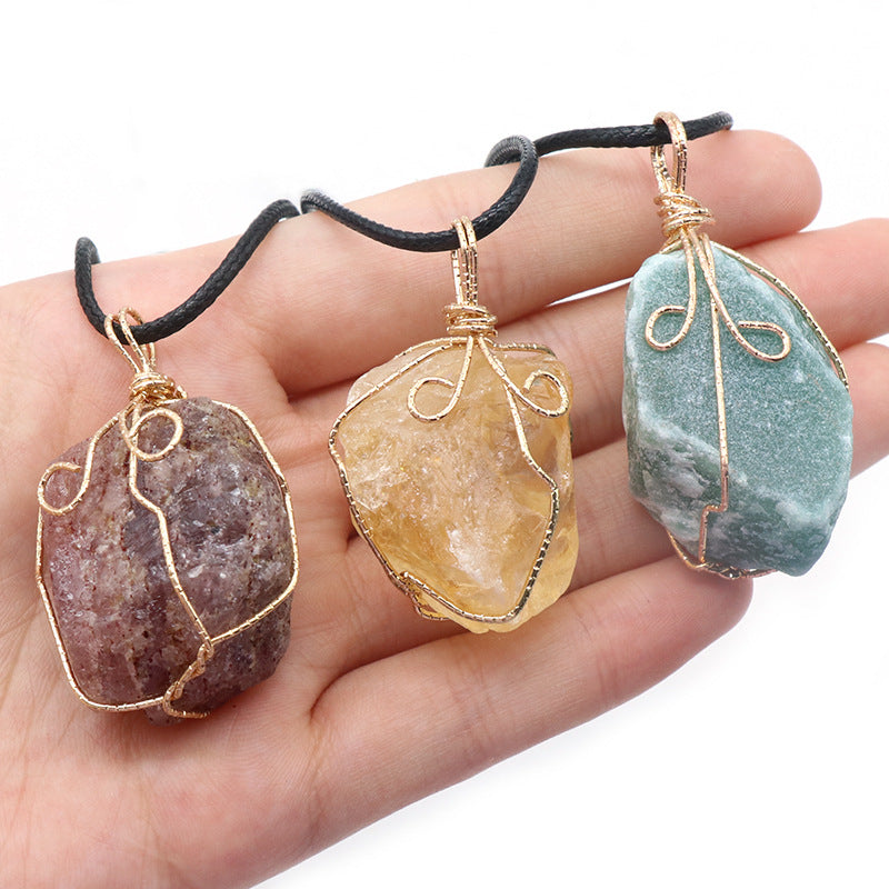 Three stone pendants on black cord held in a hand against a white background