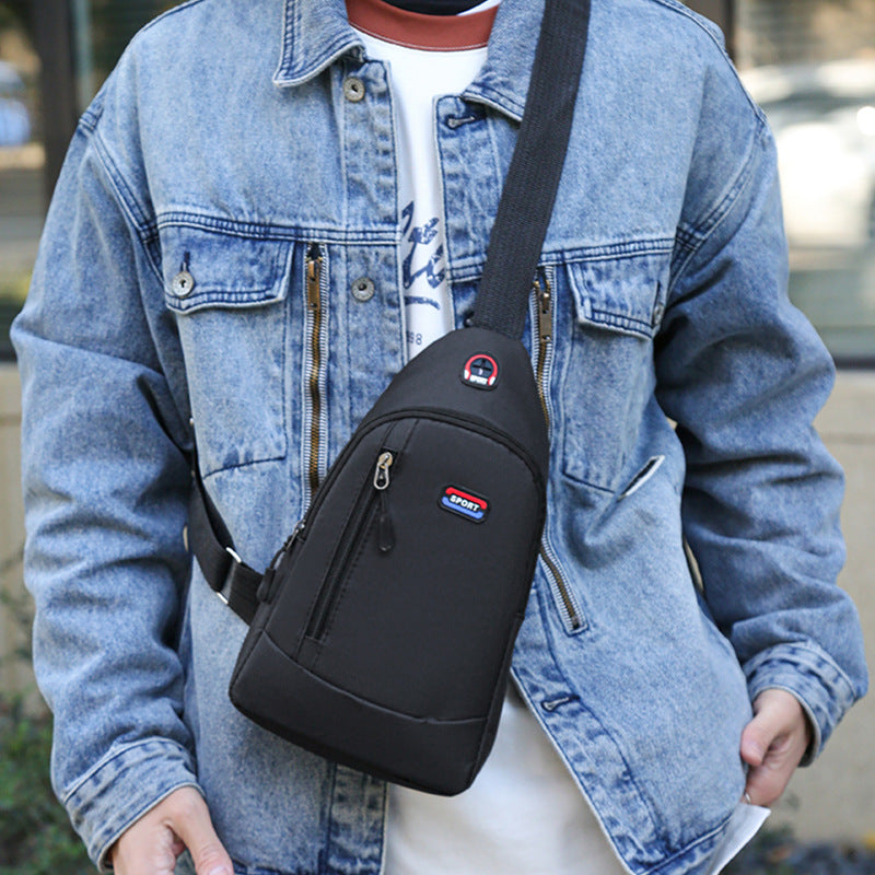 Person wearing a black sling bag with a visible brand logo, standing outdoors.