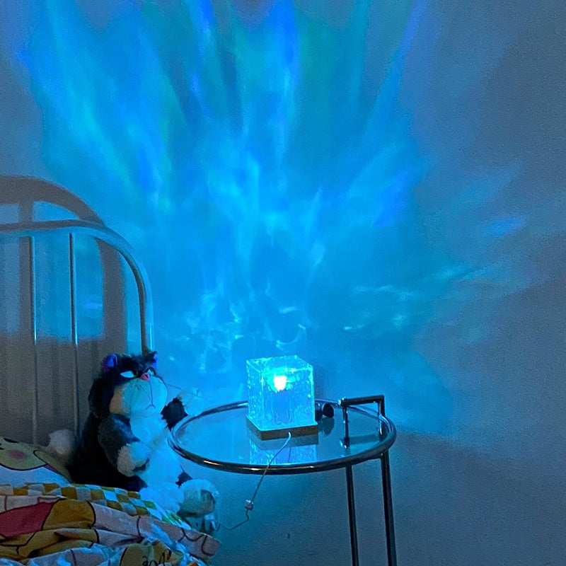 Colorful light projection on a wall with a small table and plush toy in the foreground.