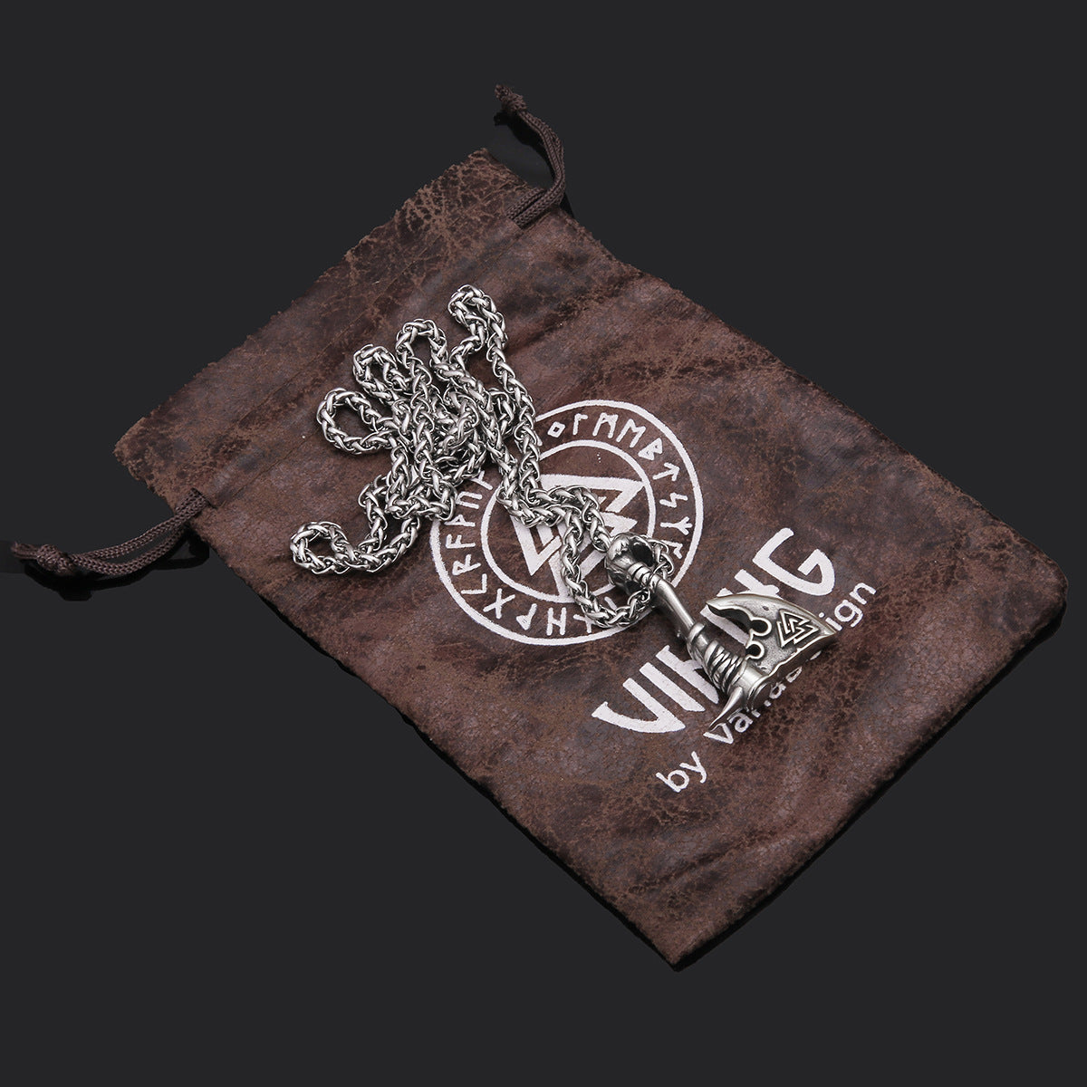 Silver necklace with decorative elements on a branded brown drawstring bag.