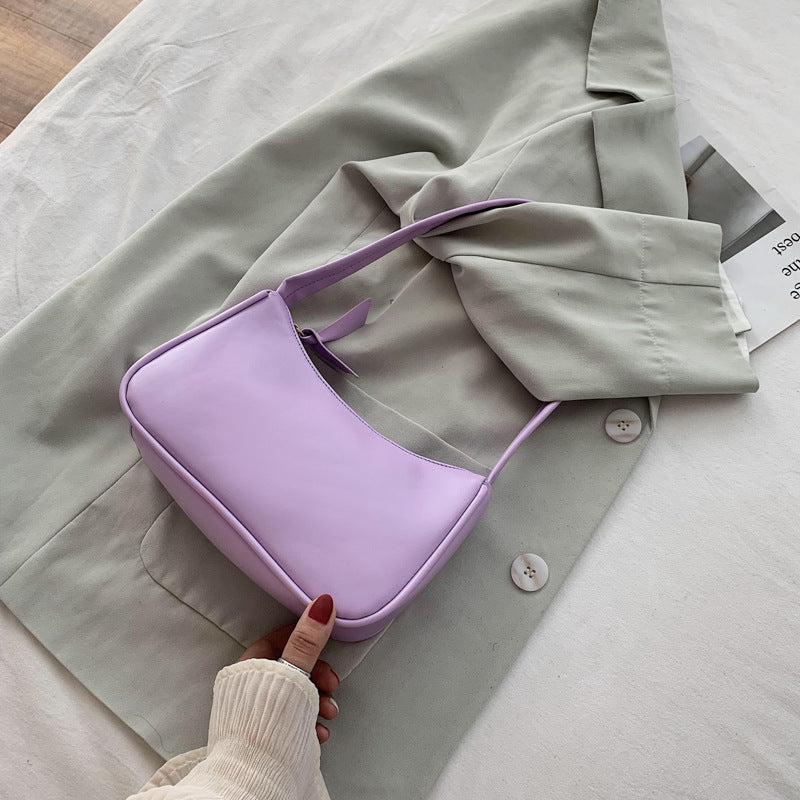 Purple handbag on a light gray coat with a hand touching it