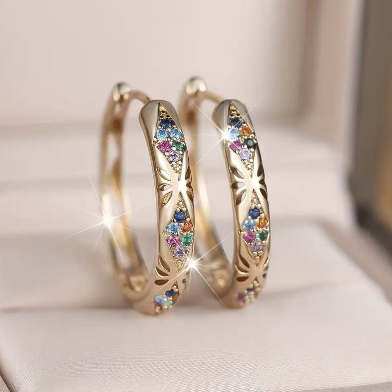 Gold hoop earrings with colorful gemstones on a soft background