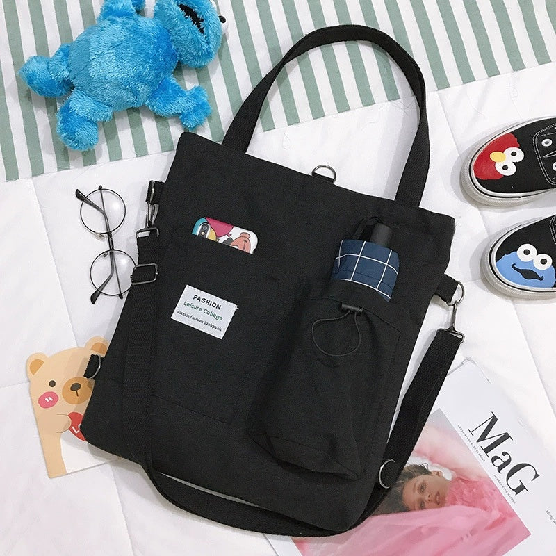 Black tote bag with colorful label on a surface with various items