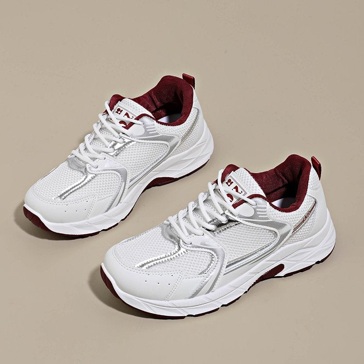 White running shoes with maroon accents on a beige background