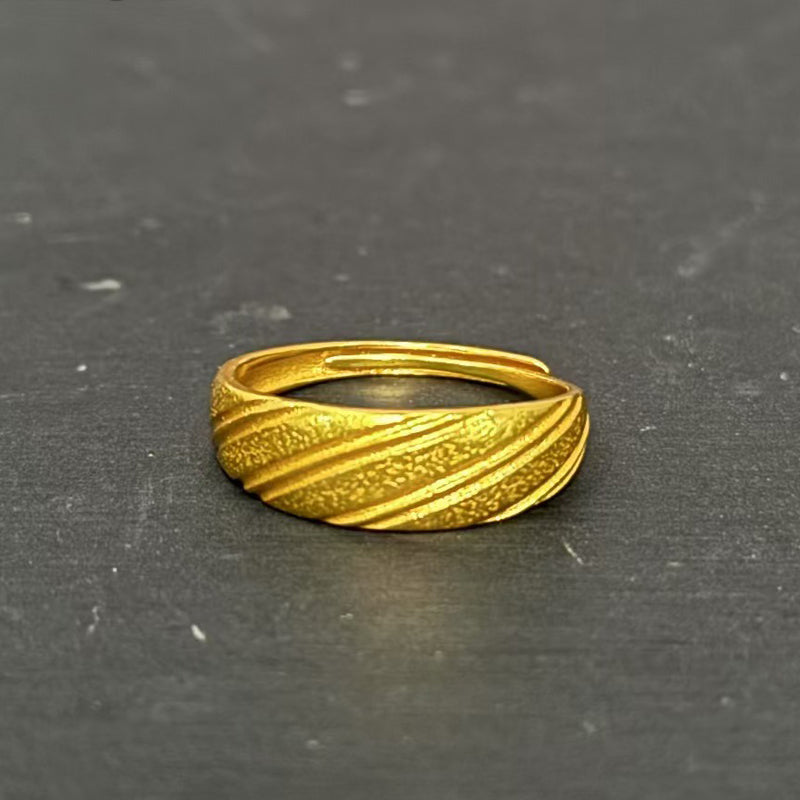 Gold ring with textured design on a dark gray background