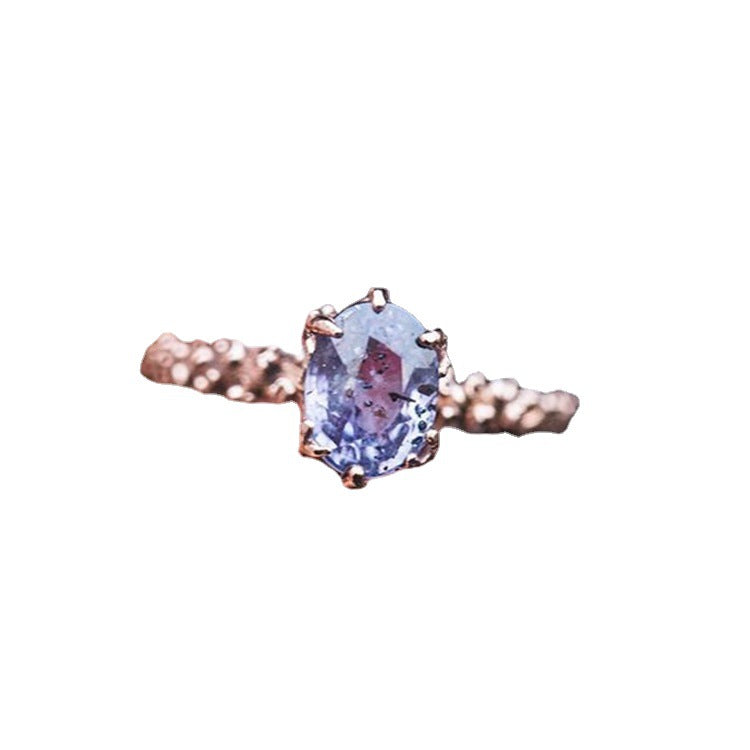 Rose gold ring with a purple gemstone on a white background