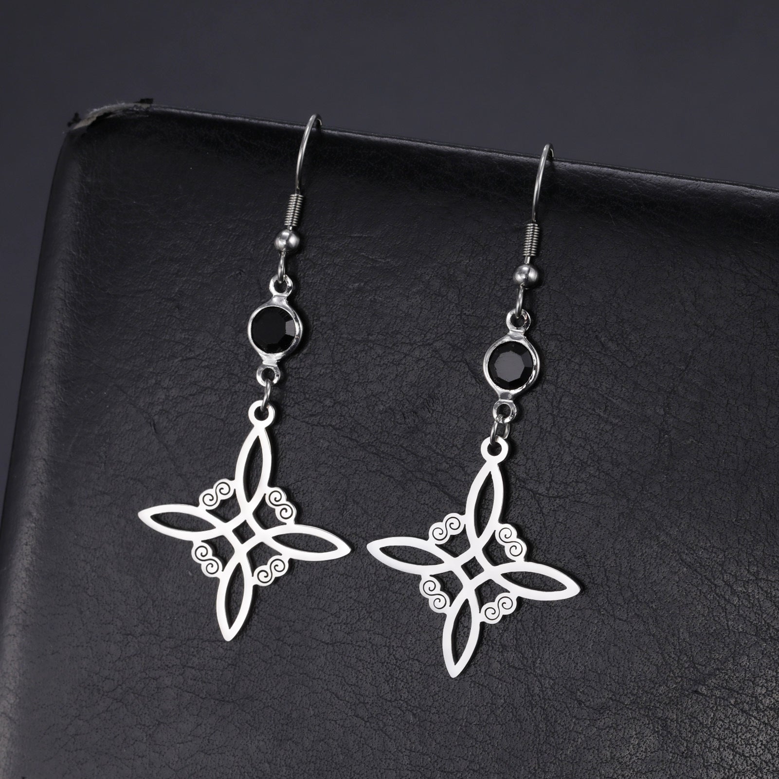Silver star-shaped earrings on a black background