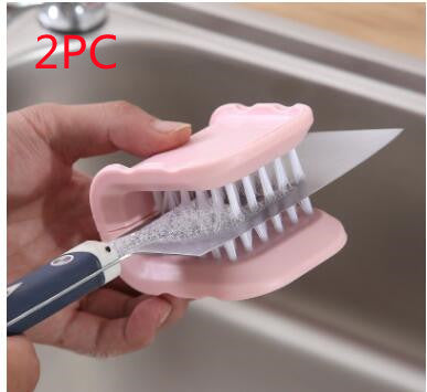 Knife with a pink cleaning brush held by a hand, with a sink in the background.