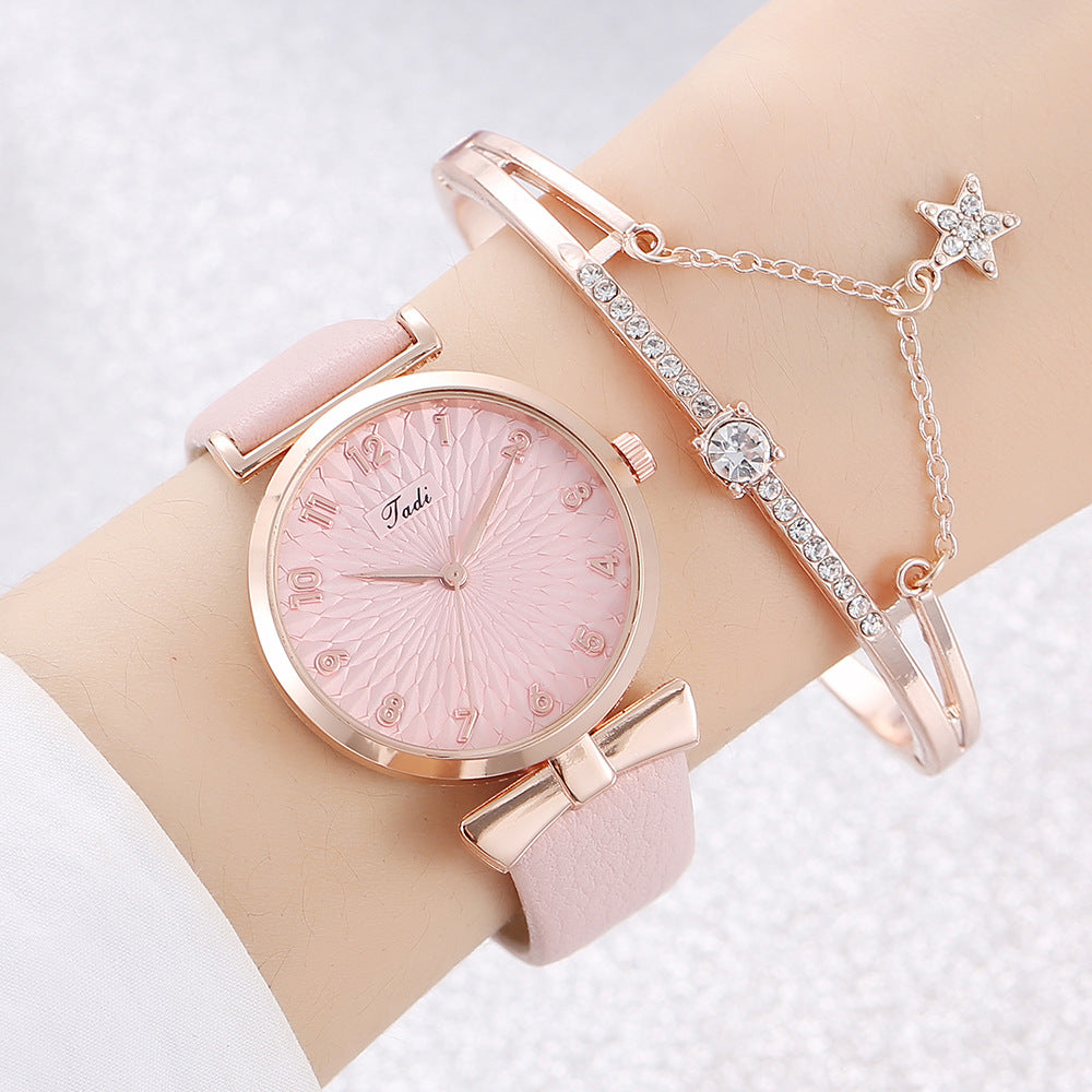 Pink watch with rose gold strap and bracelet on a wrist against a light background