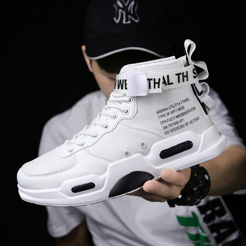 White high-top sneaker with text design held by a person wearing a black cap.