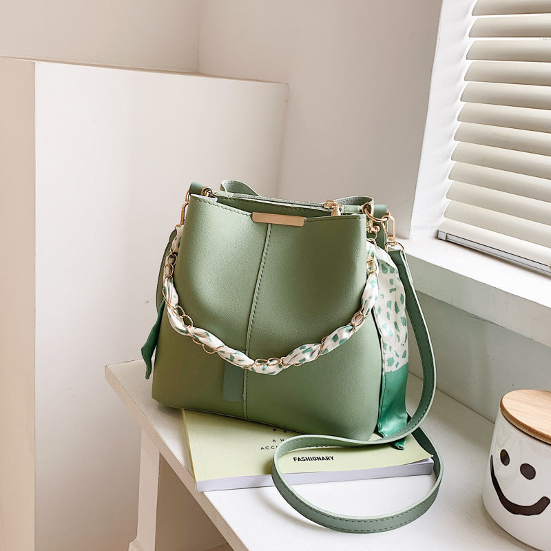 Green handbag with a floral strap on a white surface