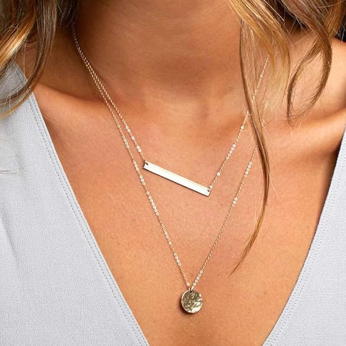 Close-up of a person wearing two necklaces with a light background