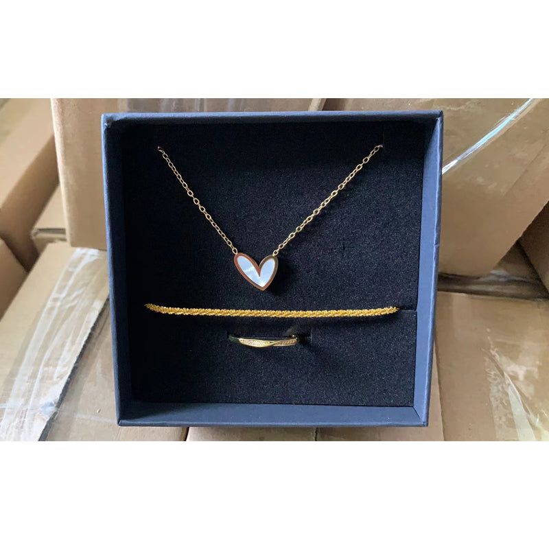 Gold necklace with a heart-shaped pendant in a black box on a cardboard surface
