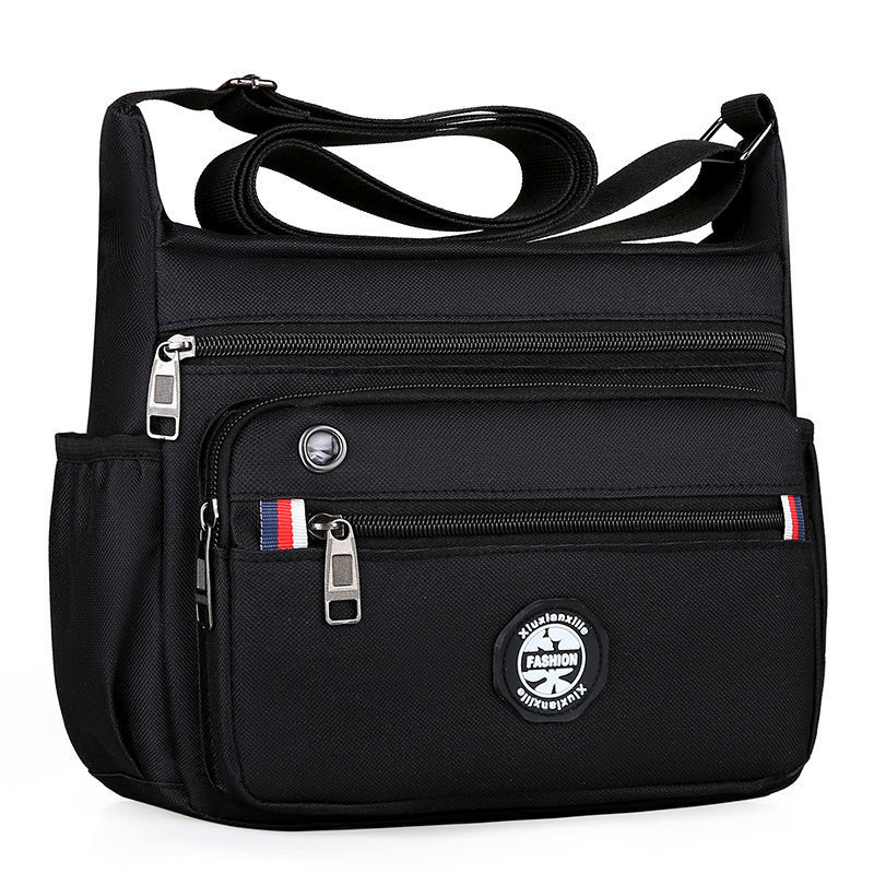 Black crossbody bag with multiple zippers and a visible brand logo on a white background