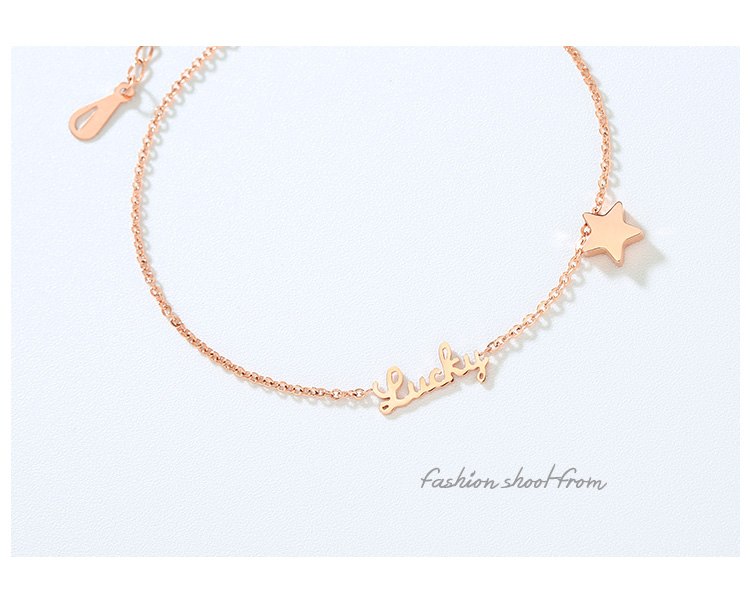 Rose gold bracelet with star and heart charms on a light blue background