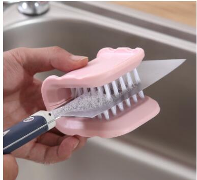 Person holding a knife with a pink brush attachment over a sink.