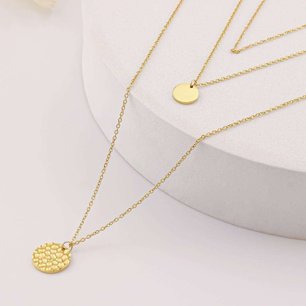 Gold necklaces with round pendants on a white surface