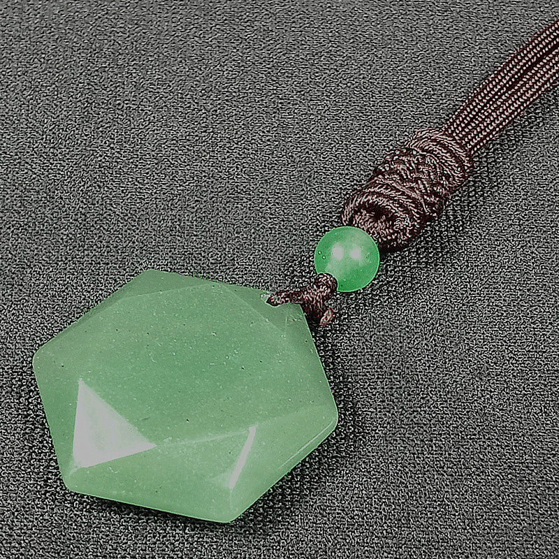 Green faceted stone pendant on a brown cord against a gray background