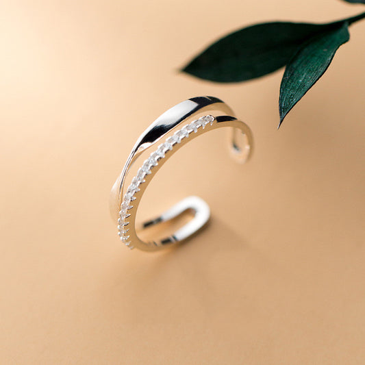 Silver bracelet on a beige background with green leaves
