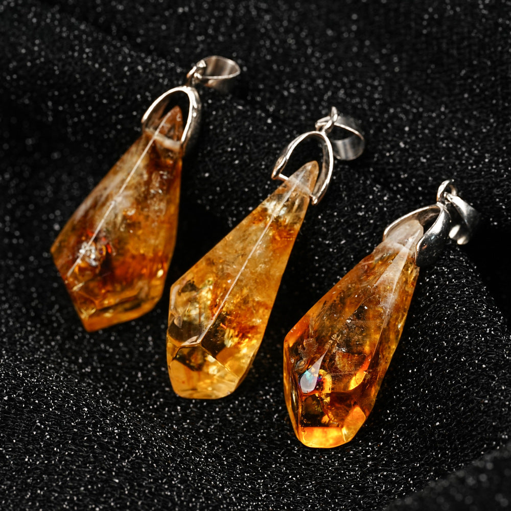 Three amber teardrop pendants on silver hooks against a dark background