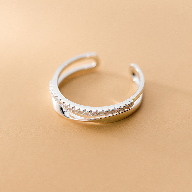 Silver ring with textured design on a beige background
