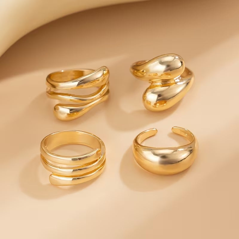 Four gold rings on a beige background