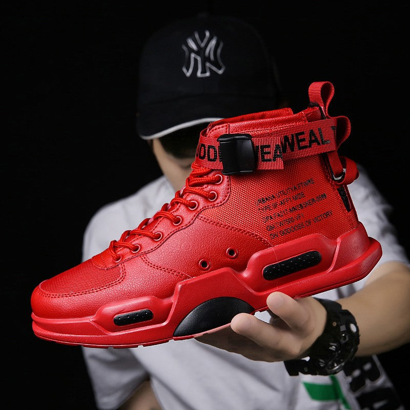 Red high-top sneaker held by a person wearing a black cap with white logo on a dark background
