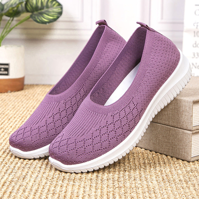 Purple slip-on shoes with white soles on a woven surface.