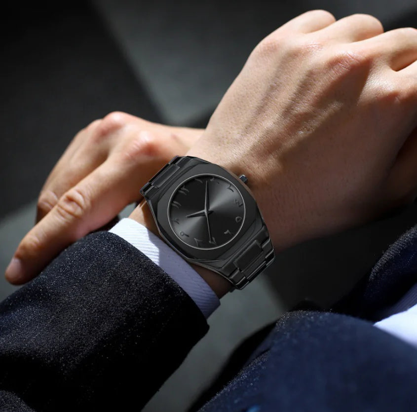 Person wearing a black wristwatch on a blurred background