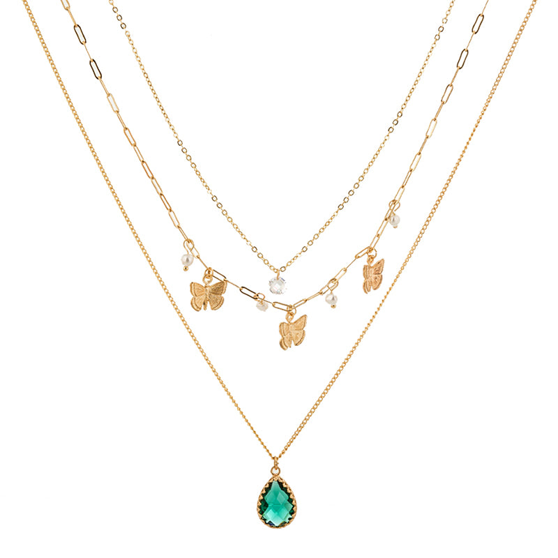Three gold necklaces with butterfly and green teardrop pendants on a white background