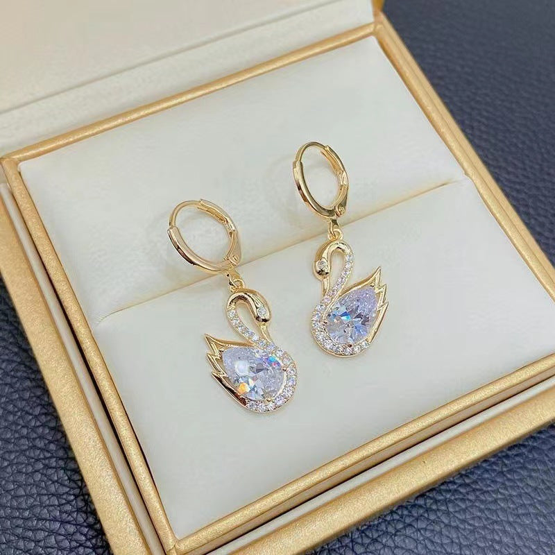 Gold earrings with clear gemstones in a jewelry box