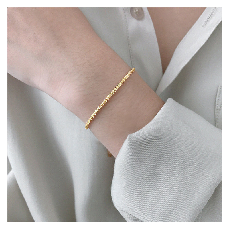 Gold bracelet on a person's wrist with a light background