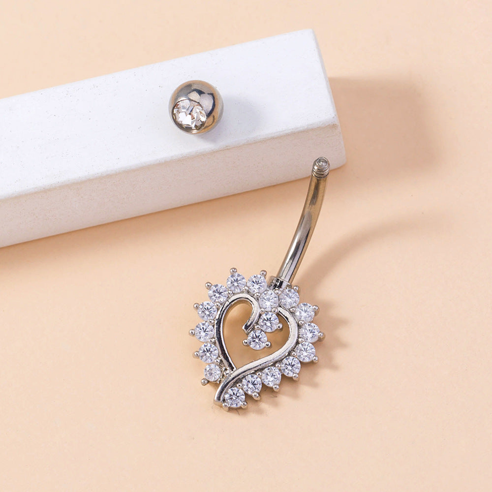 Silver belly button ring with heart design on a beige background