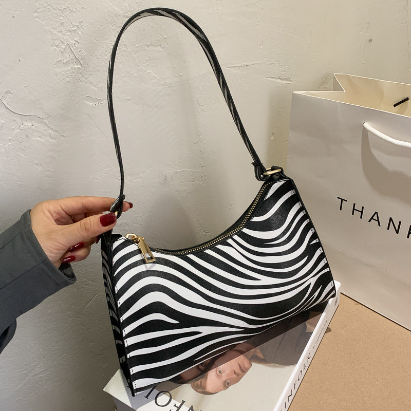 Black and white zebra-striped handbag held by a person with a 'THANK' branded bag in the background.