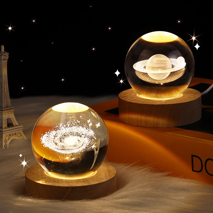 Two crystal ball night lights with planetary design on wooden bases, Eiffel Tower in the background.