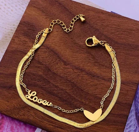 Gold bracelet with 'Love' engraving on a wooden surface