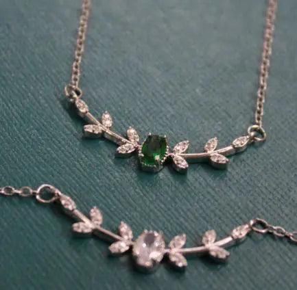 Silver necklace with green gemstone on a teal background