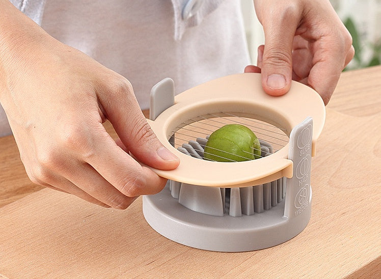 Person using a kitchen tool to slice a lime on a wooden surface
