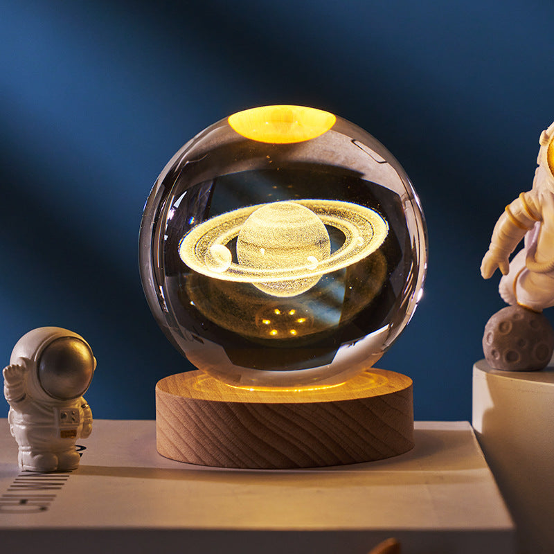 Glass sphere with Saturn model on a wooden base against a dark blue background