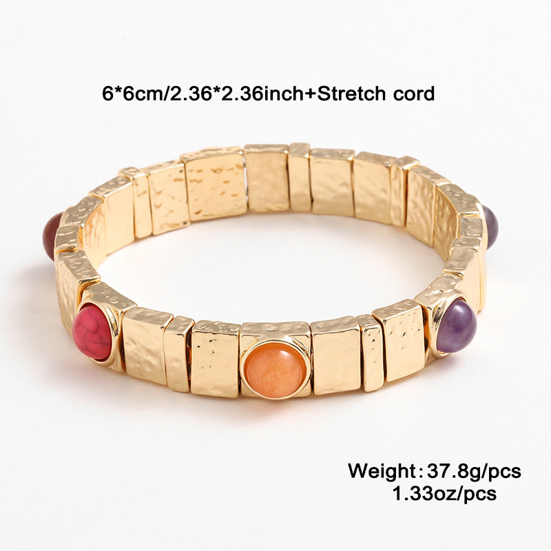Gold bracelet with colorful stones on a white background