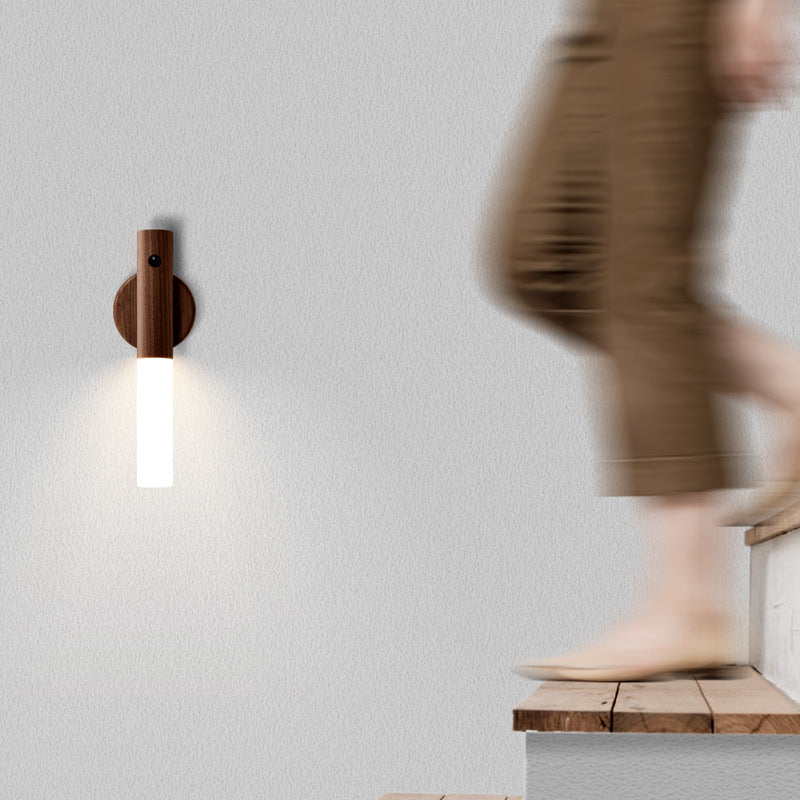 Wall-mounted light fixture on a plain wall with a blurred person in the background
