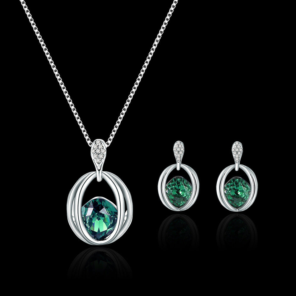 Silver jewelry set with green gemstones on a black background