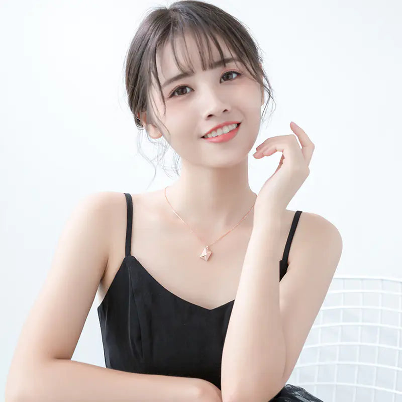 Woman wearing a black top and a necklace with a heart pendant on a white background