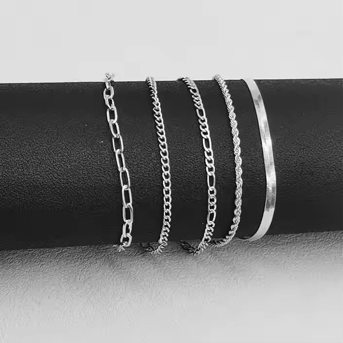 Set of silver necklaces and a bracelet on a black cylindrical object with a gray background