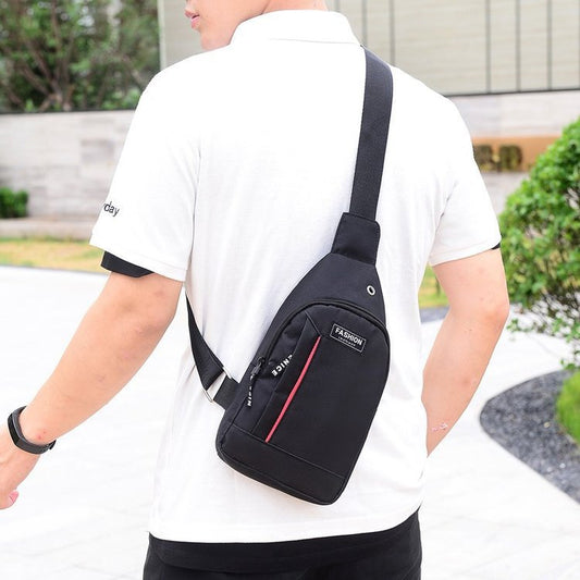 Person wearing a black crossbody bag with a visible brand logo outdoors.