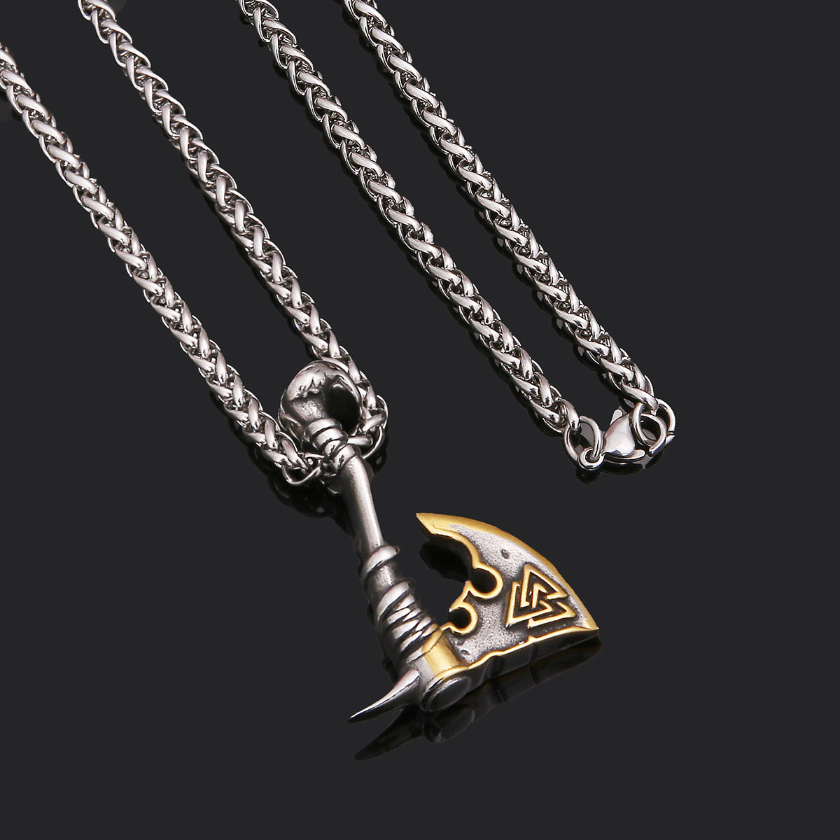 Silver and gold axe-shaped pendant on a chain against a black background