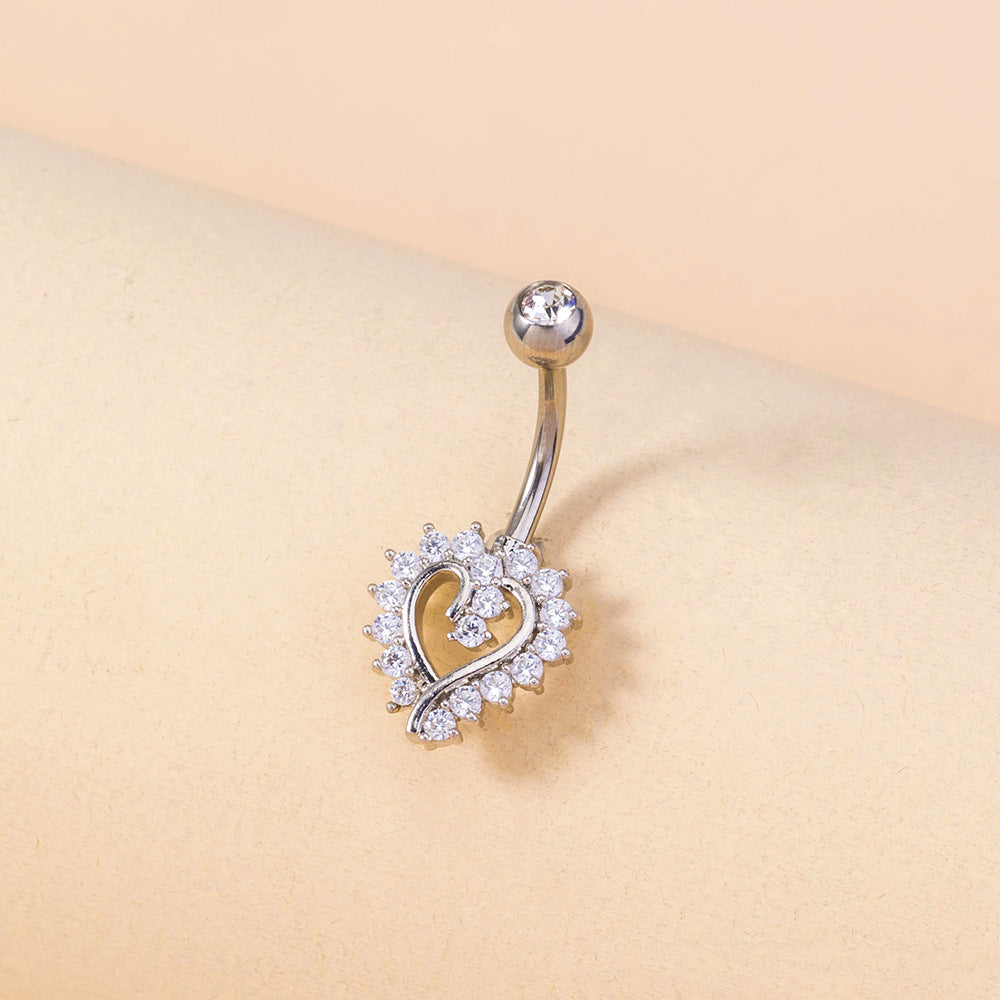 Heart-shaped belly button ring with clear stones on a beige background