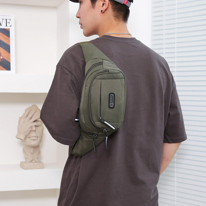 Person wearing a green sling bag over one shoulder indoors.